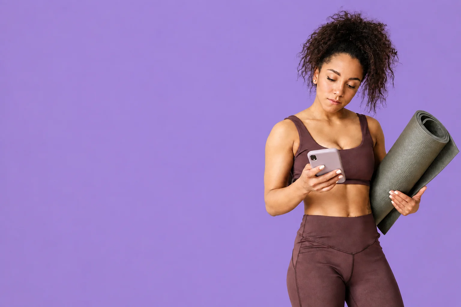 A yoga practitioner holding her phone and mat